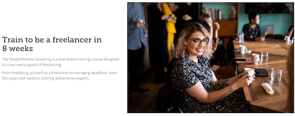 A gir sitting behind a table and smiling while having cofee