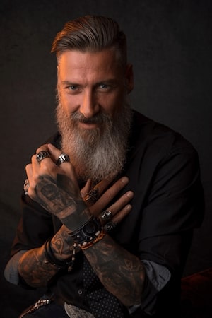 A man wearing jewelry on his hands with white beard