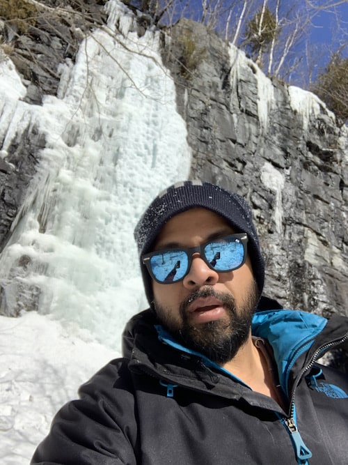 A man wearing glasses behind a mountain wall