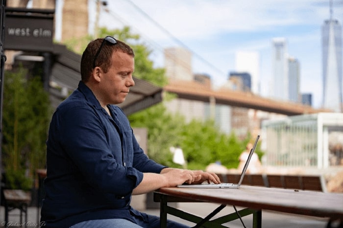 man working on his laptop outside of the balcony of a hotel